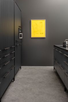 a kitchen with black cabinets and yellow painting on the wall in it's center