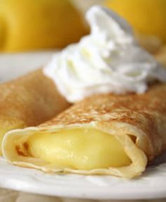 a crepe on a plate with whipped cream and lemons in the background