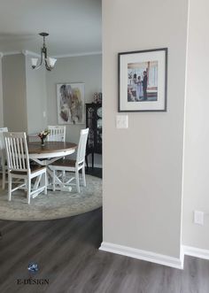 a dining room table and chairs in front of a wall with pictures hanging on it