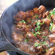 a pan filled with meat and vegetables cooking on top of a stove