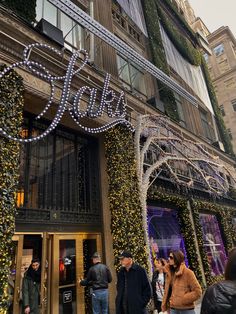 people are walking in front of a store decorated with christmas lights