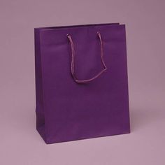 a purple shopping bag sitting on top of a white table next to a black wall