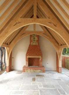 an empty room with a brick fireplace in the center and wood beams on the ceiling