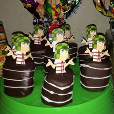 chocolate covered desserts with cartoon figures on them sitting on a green platter next to candy