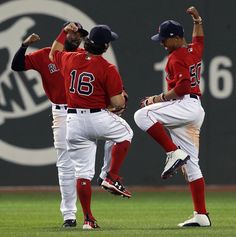 three baseball players in red and white uniforms standing on the field with their hands up