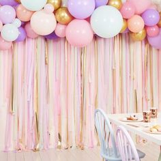 a party with balloons and streamers hanging from the ceiling, along with pastel colors