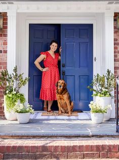 a woman standing in front of a blue door with her dog sitting on the steps