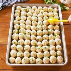 a pan filled with dumplings on top of a wooden table next to garlic and parsley