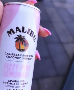 a person holding up a pink and white drink in their left hand, with palm trees on it