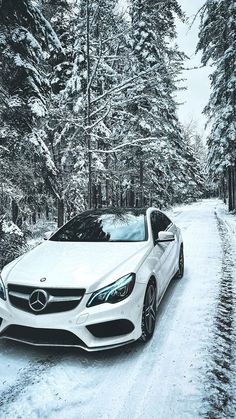 a white car parked on the side of a snow covered road in front of trees