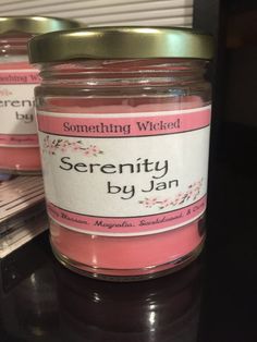 two jars of pink candles sitting on top of a table