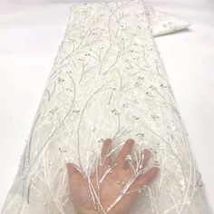 a person's hand on top of a white cloth covered in beads and sequins