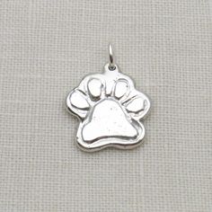 a silver dog paw charm on a white background