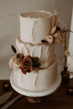 a three tiered wedding cake with feathers and flowers