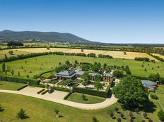 an aerial view of a large house in the middle of a lush green field with trees