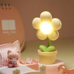 a small flower lamp sitting on top of a table next to a stuffed animal toy