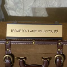 a piece of luggage with a sign that says dreams don't work unless you do