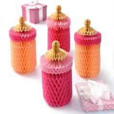 four pink and orange honey jars with tissue paper on the table next to one another