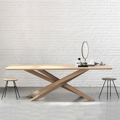 a table and two stools in front of a white brick wall with a mirror on it