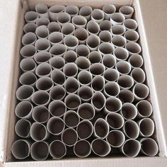 a box filled with lots of grey plastic cups on top of a table next to a white wall