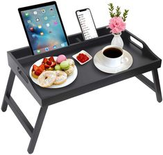 a laptop computer sitting on top of a table next to a plate of food and drink