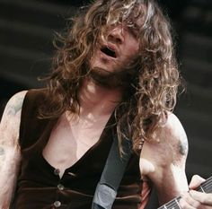 a man with long hair playing an electric guitar