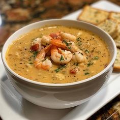 a bowl of soup with shrimp and crackers on the side, ready to be eaten