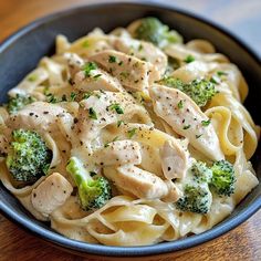 pasta with chicken, broccoli and parsley in a blue bowl on a wooden table