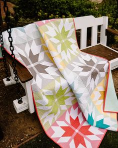 a white bench with a colorful quilt on it