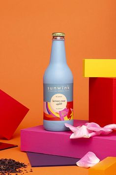 a blue bottle sitting on top of a table next to pink and yellow pieces of paper