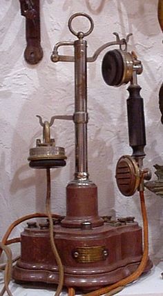 an old fashioned telephone is on display in a room with other antique phones and wall hangings