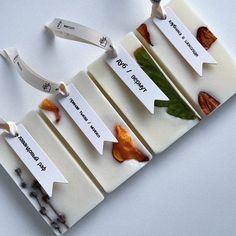 four pieces of food with labels attached to them on a white surface, including carrots and leaves