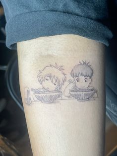 a couple of people sitting on top of a table next to each other with tattoos on their legs