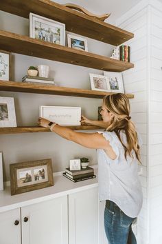 a woman is standing in front of shelves with pictures and books on top of them