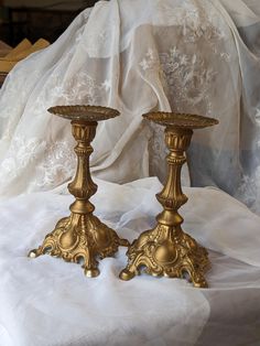 two golden candlesticks sitting on top of a white cloth