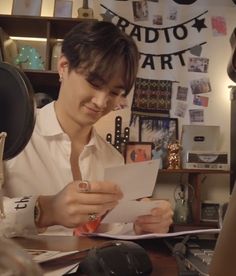 a young man sitting at a desk reading a piece of paper