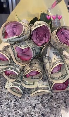 a bunch of rolled up money sitting on top of a counter next to a vase filled with flowers