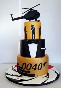 a three tiered cake decorated with black and yellow fondant, an helicopter on top