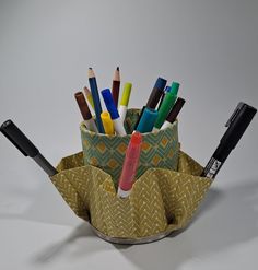 a pen holder filled with lots of different colored pencils and crayons in it