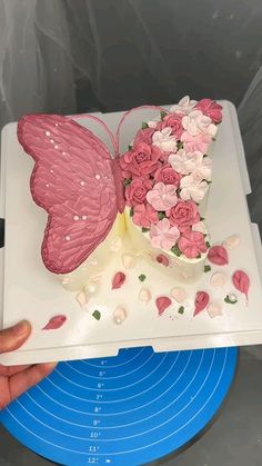 a butterfly shaped cake with pink and white flowers in it's wings on a blue plate