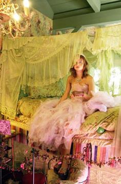 a woman sitting on top of a bed in a room filled with furniture and decor