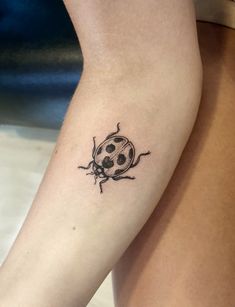 a ladybug tattoo on the left thigh and right leg, with black ink