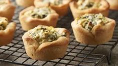 several small muffins with spinach and cheese in them on a cooling rack