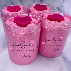 four jars filled with pink hearts on top of a marble counter next to each other