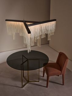 two chairs and a table in a room with lights hanging from it's ceiling