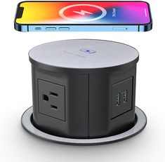 an electronic device with a charging station attached to it and a phone in the background