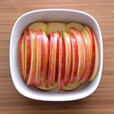 sliced apples in a white bowl on a wooden table