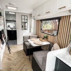 the interior of an rv with wood flooring and white walls, including a dining area