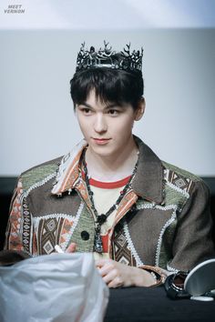 a young man wearing a crown sitting at a table