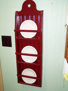 a red shelf with plates on it next to a wall